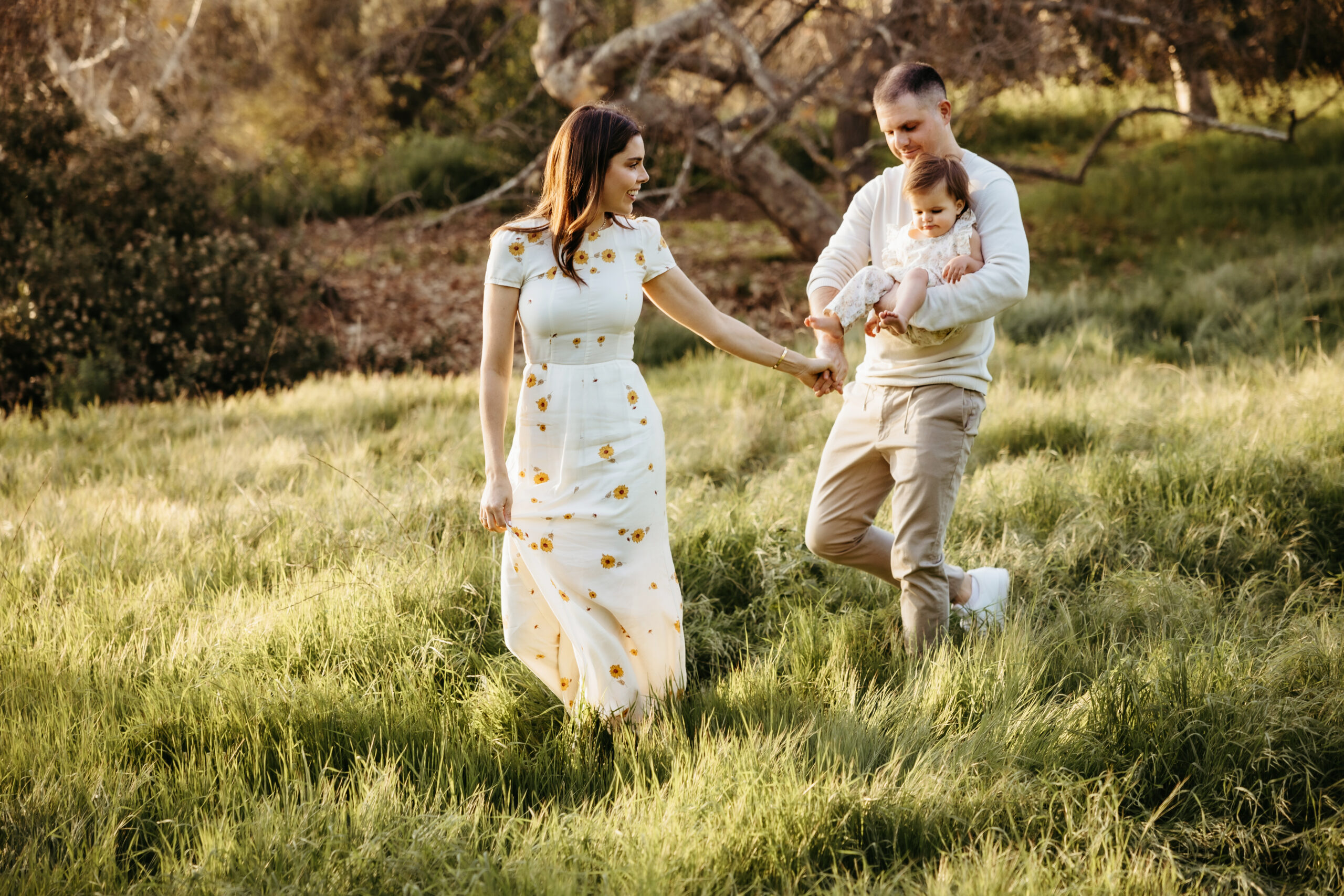 mother and father walking through a grassy field in los angeles ca during a family photo shoot with Among the Wildflowers Photography